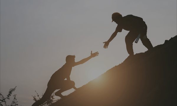 One person helping another up a slope